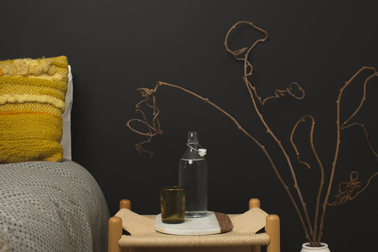 Indoor decor with glass water bottle and brown glass on bedside table